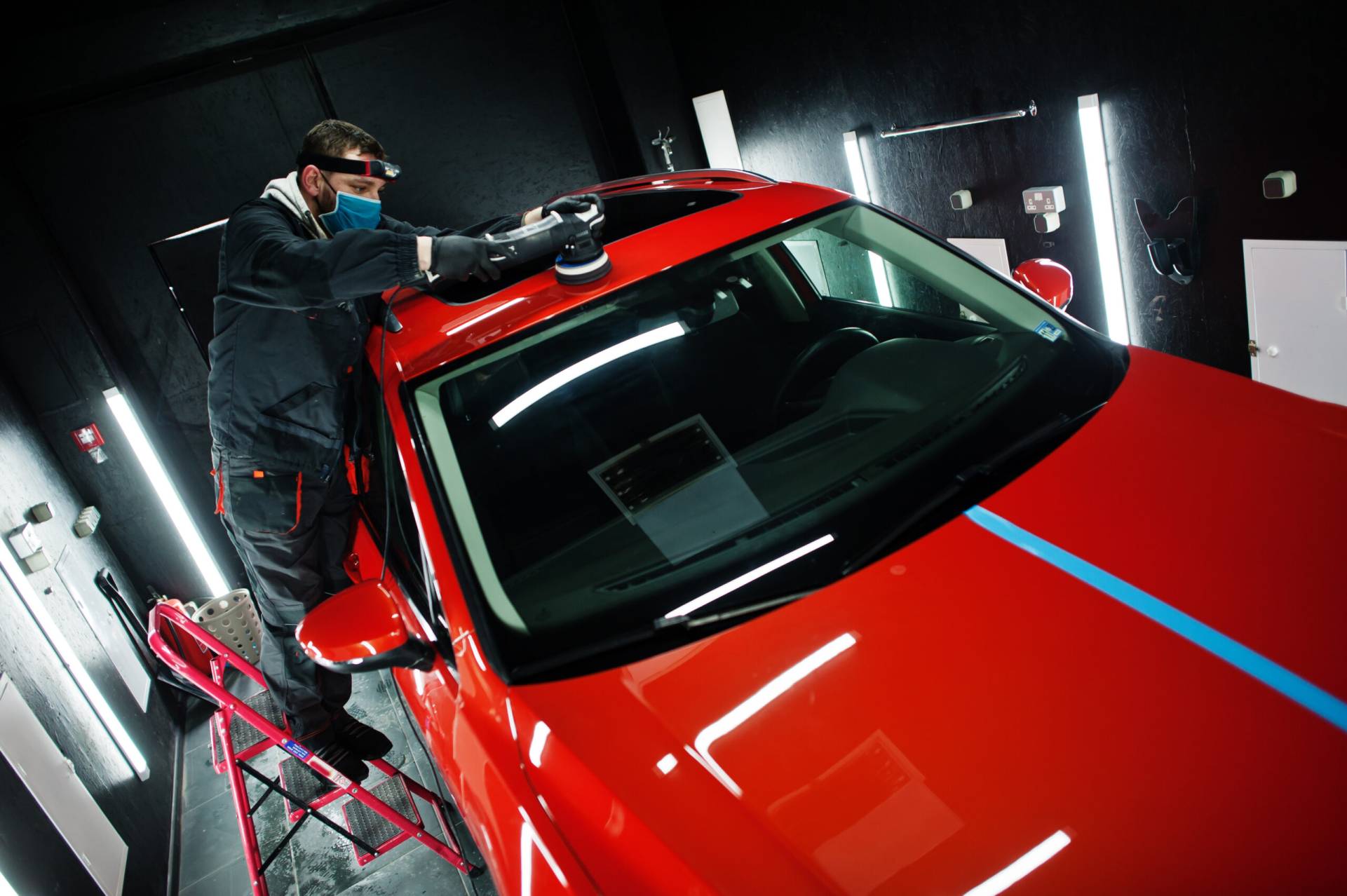 About car detailing concept. man in face mask with orbital polisher in